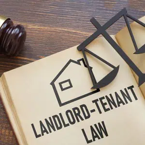 Book titled 'Landlord-Tenant Law' with a wooden justice scale and gavel nearby - Hudson Martin PC