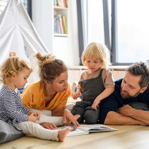 Happy blended family of four reading a book on the floor, relevant to estate planning.